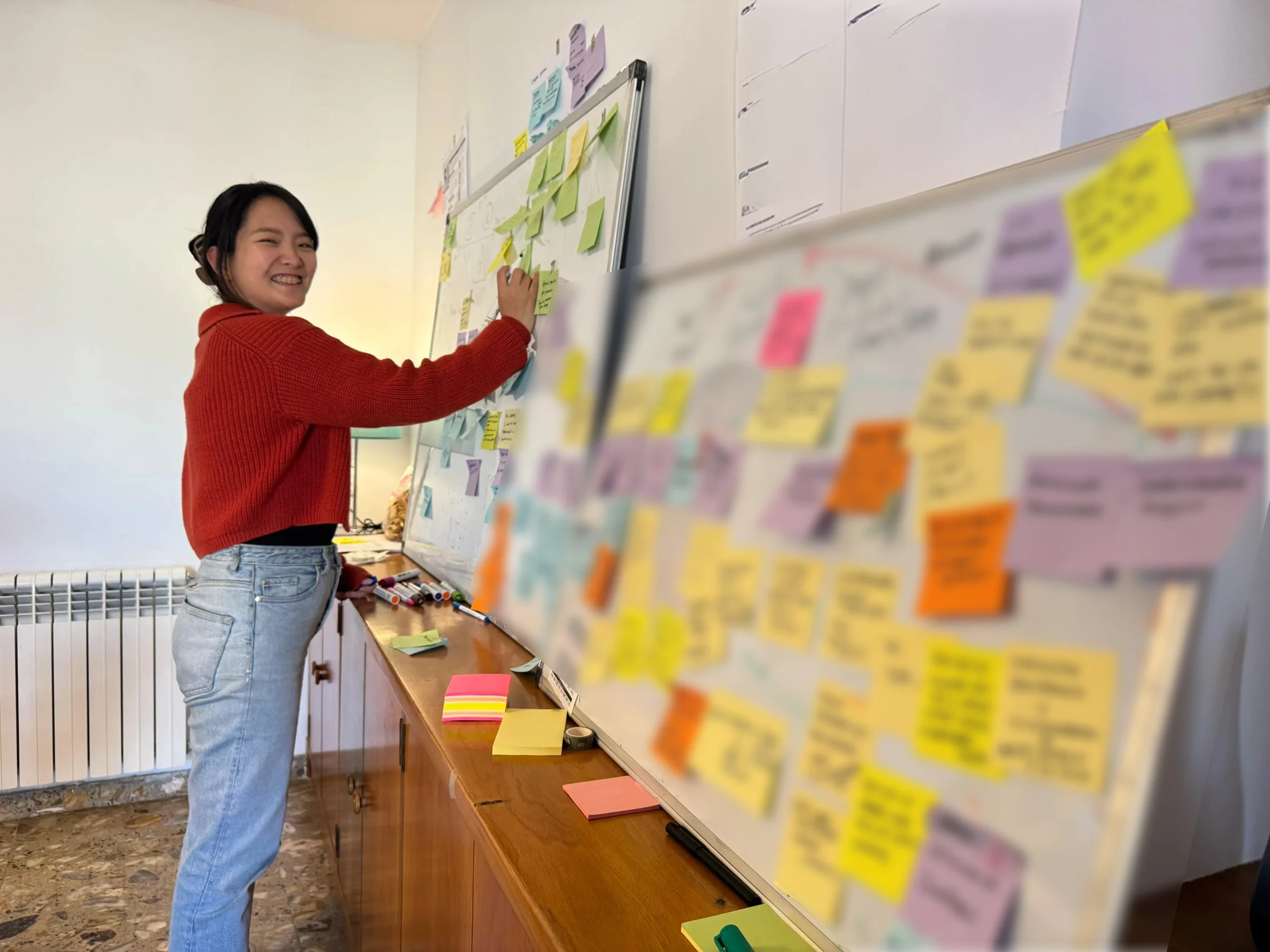 Yuna organizing research notes on a whiteboard during a workshop