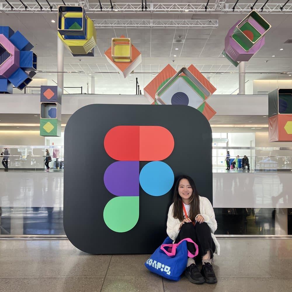 Yuna sitting next to a giant Figma logo sculpture