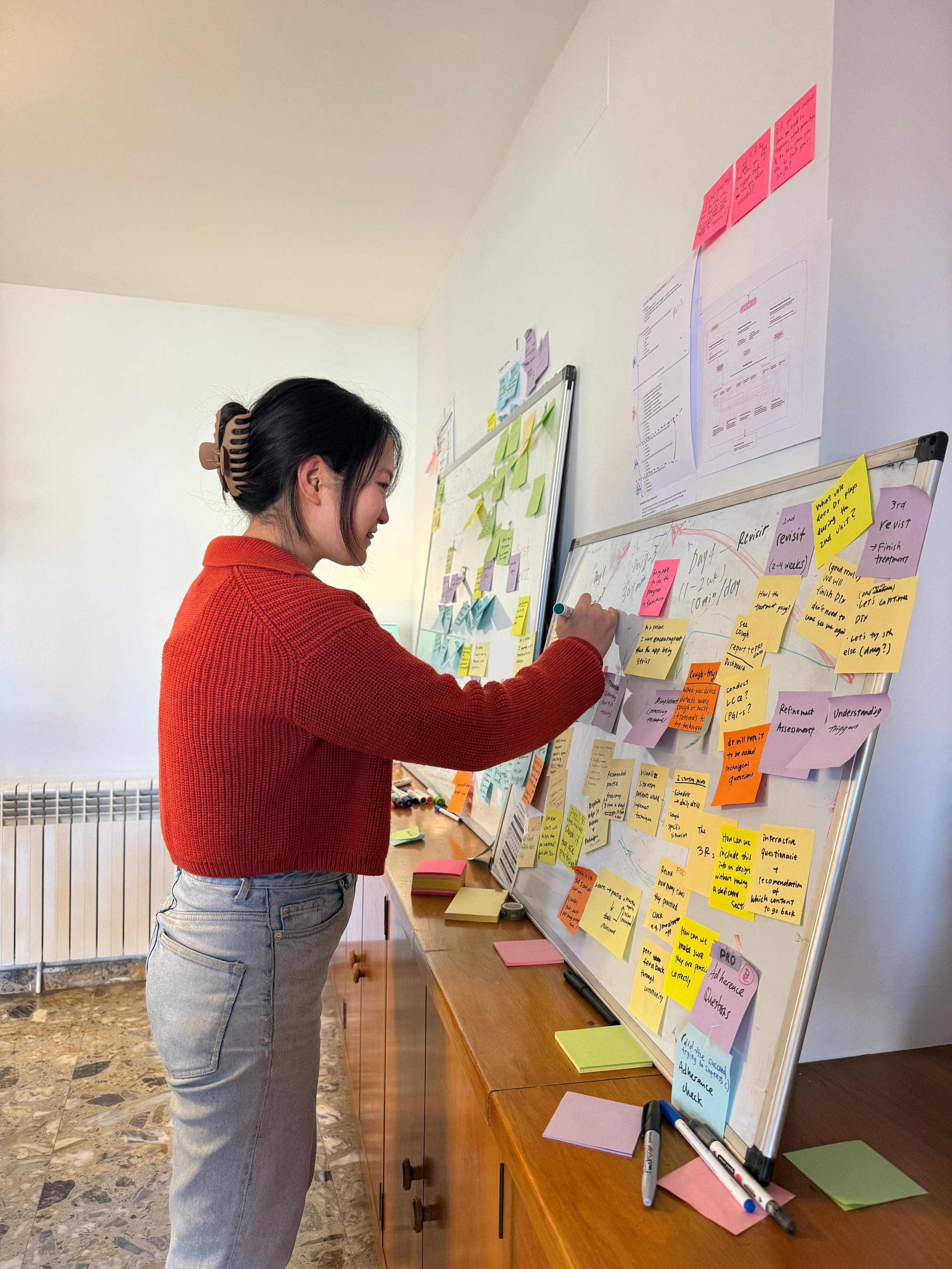 Yuna organizing research notes on a whiteboard during a workshop